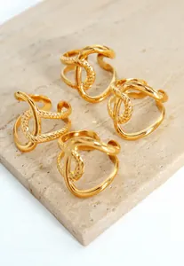 Detail von vier goldfarbenen verschlungenen Ringen auf einer natürlichen Travertinsteinbasis