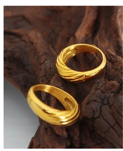 Macro di un anello in titanio dorato con trama a spirale su sfondo di legno