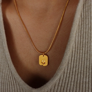 Elegante goldene Schlangenkette mit Smile-Gravur Anhänger am Hals eines Models