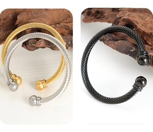 Dettaglio di tre bracciali rigidi a spirale in finitura oro, argento e nero