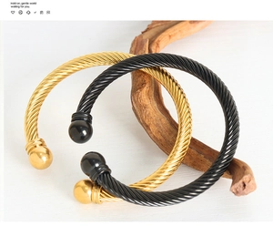 Dettaglio dei bracciali a corda intrecciata in oro e nero con terminali a sfera