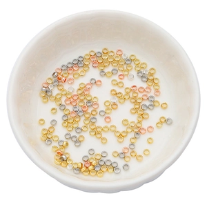 Polished gold, silver and rose gold crimp beads for jewelry making in a white bowl