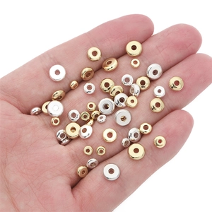 Flat round gold and silver spacer beads for DIY jewelry making shown on hand for scale