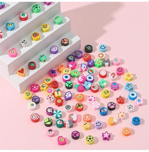 Gros plan de perles colorées en argile avec sourires et motifs de fruits pour DIY
