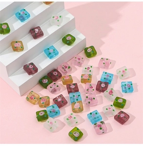 Macro detail of square frosted glass beads with hand-painted floral patterns for DIY jewelry