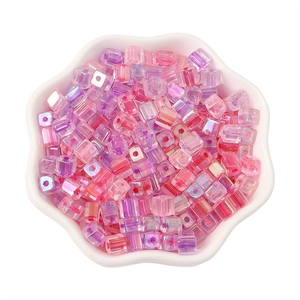 Pink and purple gradient 5mm square glass beads with iridescent finish in a white bowl