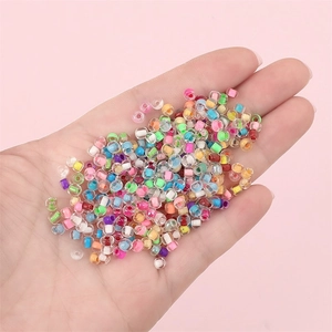 Cuentas de vidrio multicolores de 2mm para joyería DIY sostenidas en mano sobre rosa