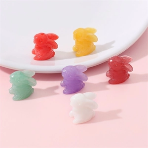Set of six colorful resin rabbit charms for DIY jewelry making on a pink background
