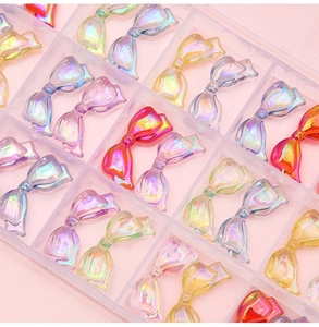 Macro view of colorful aurora acrylic bow beads for DIY craft charms in a grid box