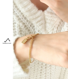 Detail van 18K vergulde titanium stalen armband met parels en een goudstaaf hanger