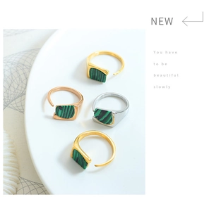 Close-up of geometric titanium steel rings with green malachite inlay and open design