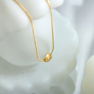 Elegante collana dorata con ciondolo a fagiolo intrecciato e catena a serpente lucida