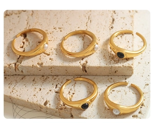 Nahaufnahme von fünf goldenen offenen Ringen mit schwarzen und weißen Glasperlen