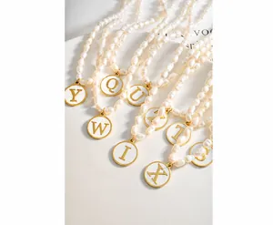 Macro shot of freshwater pearl necklaces with gold initial pendants on a clean white surface