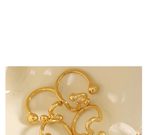 Close-up of elegant gold plated minimalist ear cuffs on a soft ceramic background