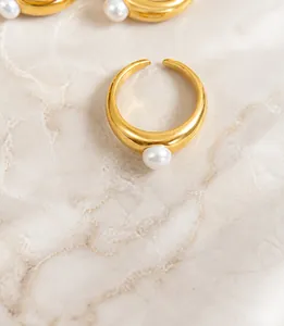 Close-up of golden open ring featuring a single pearl on a minimalist thick band