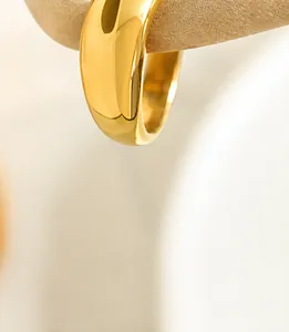 Close-up of a wide polished gold dome ring with a reflective surface and minimalist design