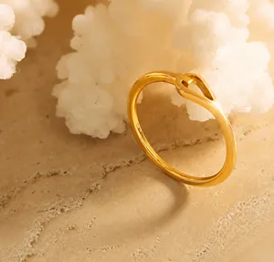 Macro shot of gold twist ring on textured rock base highlighting polished surface