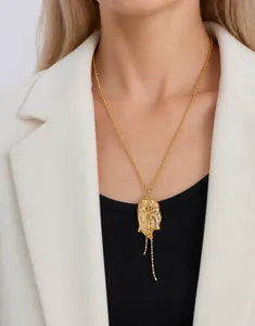 Model wearing 18K gold-plated necklace with unique face profile pendant and fringe chains
