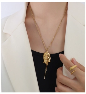 Close-up of 18K gold-plated portrait pendant necklace and textured snake ring on model