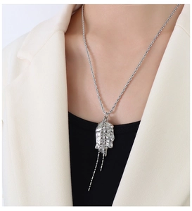 Detailed view of an abstract face pendant with tassel fringe on a thick twisted rope chain
