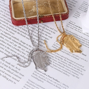 Artistic gold and silver tone portrait silhouette necklaces on a red velvet box
