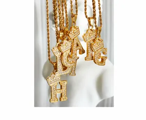 Macro detail of gold crown letter pendant necklace with sparkling zircon pave and rope chain