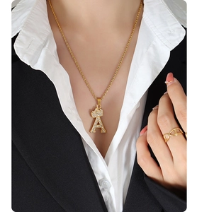 Macro shot of gold letter A pendant with crown and pavé zircons on a rope chain