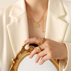 Set collana dorata con stella e anelli indossato da una modella in un blazer bianco
