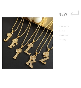 Macro detail of gold crown letter pendants with sparkling zircon pavé on rope chains