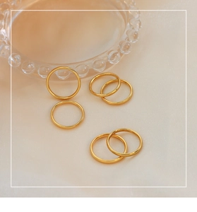 Dettaglio di sei anelli minimalisti impilabili in acciaio inossidabile placcato oro 18k