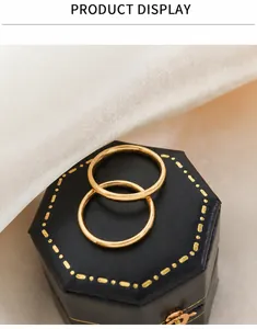 Primo piano di due anelli minimalisti placcati oro 18k su un portagioie nero esagonale
