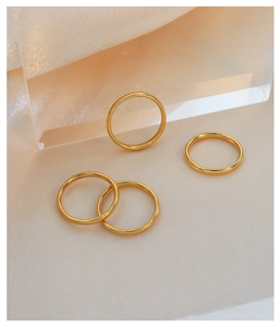 Set di anelli sottili minimalisti placcati in oro 18k su uno sfondo avorio materico