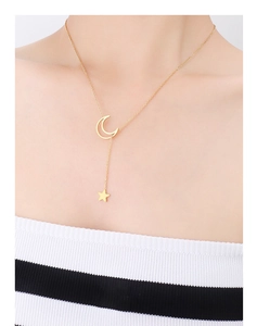 Detail view of a 18K gold star and crescent moon pendant necklace worn by a model