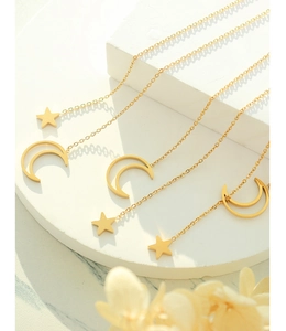 Close-up of golden star and moon pendant necklaces on minimalist white stone blocks