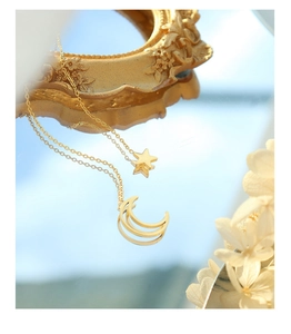 Star and moon gold pendant necklace reflected in mirror with sky background