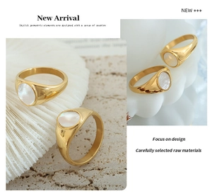 Dettaglio di anello vintage dorato con inserto in conchiglia bianca su sfondo di roccia
