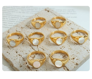 Detalle de ocho anillos dorados con incrustaciones de nácar en base de piedra