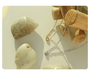 Detail of minimalist gold and silver round zircon necklaces on organic wood props