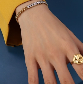 Detail of gold Cuban chain bracelet with cubic zirconia inlay and spiral relief ring