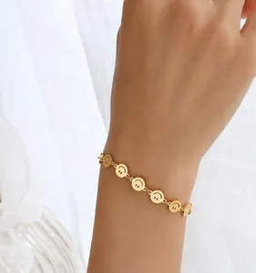 Detailed view of gold smiley face bracelet with matte finish on a wrist