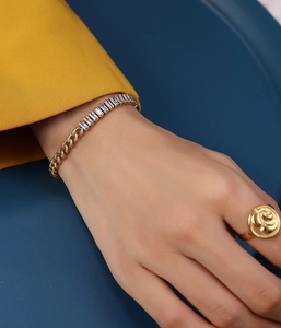 Detail of gold curb chain bracelet with baguette-cut zircon stones and matching ring