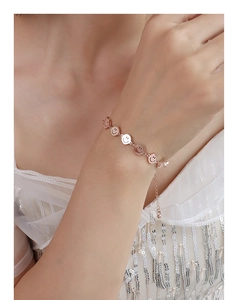 Detailed view of rose gold smiley face chain bracelet on a woman wrist with lace sleeve