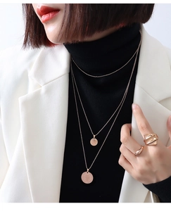 Detailweergave van gouden drielaagse muntketting met Elizabeth II hanger op een model