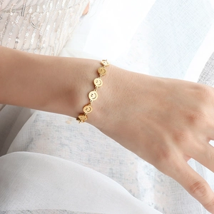 Elegant gold smiley face charm bracelet in stainless steel shown on female wrist