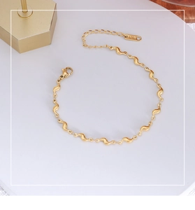 Gros plan du bracelet à vagues plaqué or 18 carats avec fermoir homard et tag K18