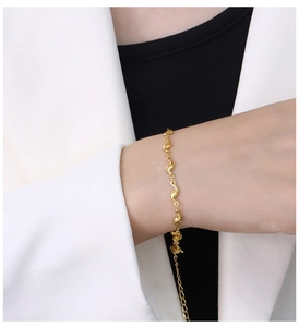 Gros plan d'un bracelet doré en acier titane porté par un mannequin en tenue chic