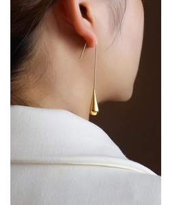 Close-up of elegant long gold teardrop earrings worn with a white suit jacket