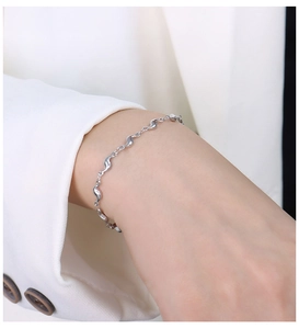 Gros plan d'un bracelet en acier titane argenté en forme de vague sur le poignet d'un modèle