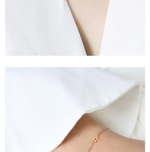 Detail van roségouden sterrenketting aan een minimalistische titaniumstalen fijne schakel